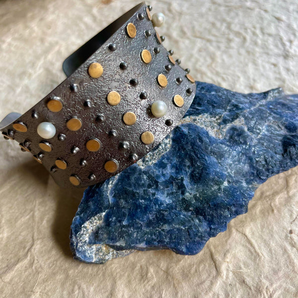 The newest addition to Mia Siya - An oxidized plated over brass bracelet cuff that so gracefully showcases artistic gold dots in addition to pearls, lavishly distributed alongside. A mild stretch would make the wear comfortable!