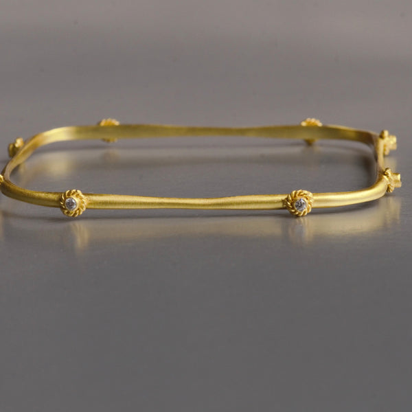 Handmade, asymmetrical, this modern bracelet is augmented with 8 cubic zirconia and artistic bezel set adorn the arm as unique wearable art. It is made with brass and plated efficiently with 18kt gold. The bracelet is 7.5 cm in diame