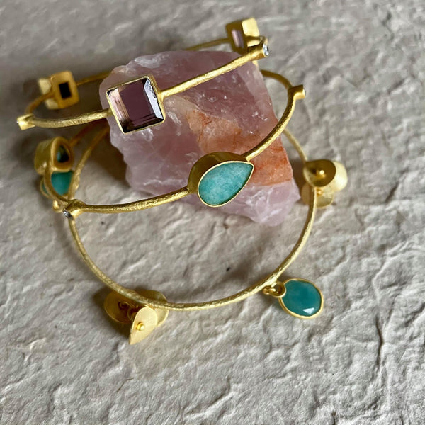 Elegant, fun, and flirtatious with its jingling soft sound, this stack is all you need as your statement piece. The set has 6 amazonites and 3 amethyst gemstones.  Pear-shaped amazonite is 9x13 in size and weighs 10.79 gms. Oval-shaped amazonite, on the other hand, is 9.78 gms in weight and the stunning square amethyst is 9.33 gms, with a total of 35.847 gms. in total.  The set is to the large side. It is 3 inches in diameter or 8 1/2 cms or 10 inches in circumference.