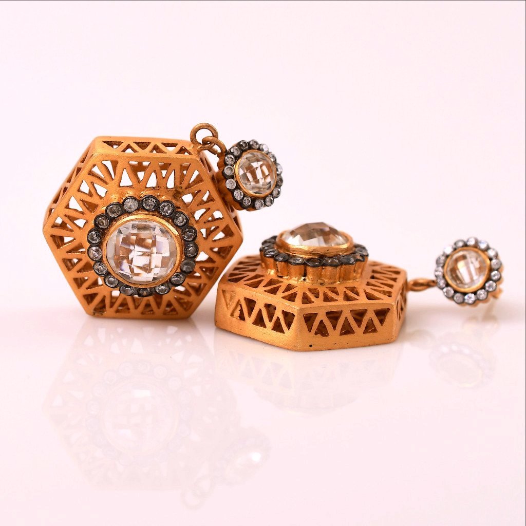 Intricately carved on both sides, these artistic hexagon shaped earrings are mysterious and intriguing. Bold cubic zirconia in the middle reflects the luminious and opulent characteristic with gratification. 18 Kt Gold plating on base metal, it flaunts elegance and sophistication.