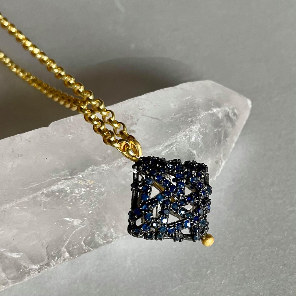 Round-shaped blue sapphires that weigh 1.87 gms and are 1.50 mm in size are studded meticulously on this stunning square-shaped pendant, which is 25x18mm in height and width. and in a .925 sterling silver necklace with 18kt gold plating. This sterling silver chain necklace with fine gold plating is 16 inches long.