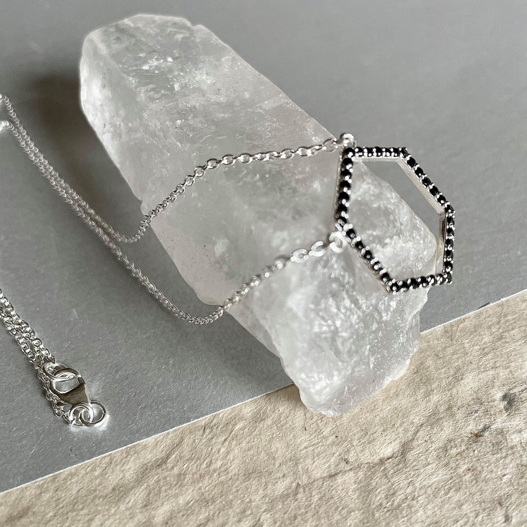 A Hexagon-shaped Amiya necklace, dainty, and delicate sterling silver necklace with a weight of 3.495 gms with adorable little black spinel gemstones with a weight of 0.7 ct. is your wear-anywhere accessory. It is 18 inches in length and has 3 adjustable rings to make your wear comfortable. The pendant is 20 mm by 22 mm in size.