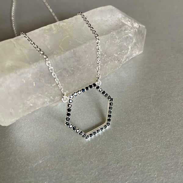 A Hexagon-shaped Amiya necklace, dainty, and delicate sterling silver necklace with a weight of 3.495 gms with adorable little black spinel gemstones with a weight of 0.7 ct. is your wear-anywhere accessory. It is 18 inches in length and has 3 adjustable rings to make your wear comfortable. The pendant is 20 mm by 22 mm in size.