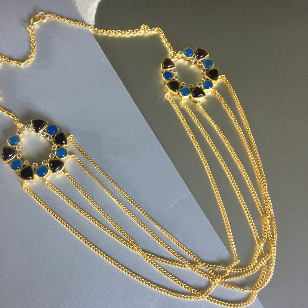 A playful necklace that may just hold your breath and keep it there for a while. An exceptional design that exudes sophistication and elegance. A chunky necklace with 2 medallions on each side flaunts a style that is unique and mysterious. Embedded with amethyst, blue chalcedony, and cubic zirconia for that perfect bling. 5 gold plated intertwined chains hung loosely and freely.