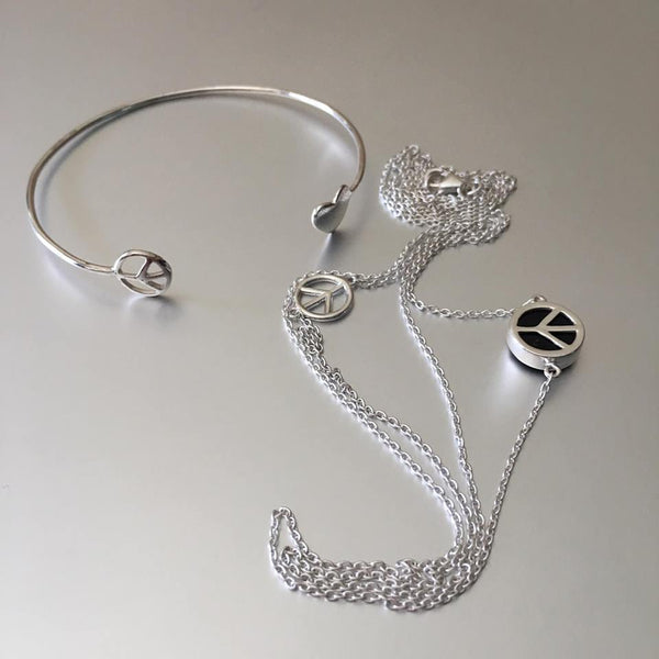 Double, sterling silver chain necklace, one longer than the other hold a plain peace sign on one chain and a chunkier one with black onyx on the longer chain.