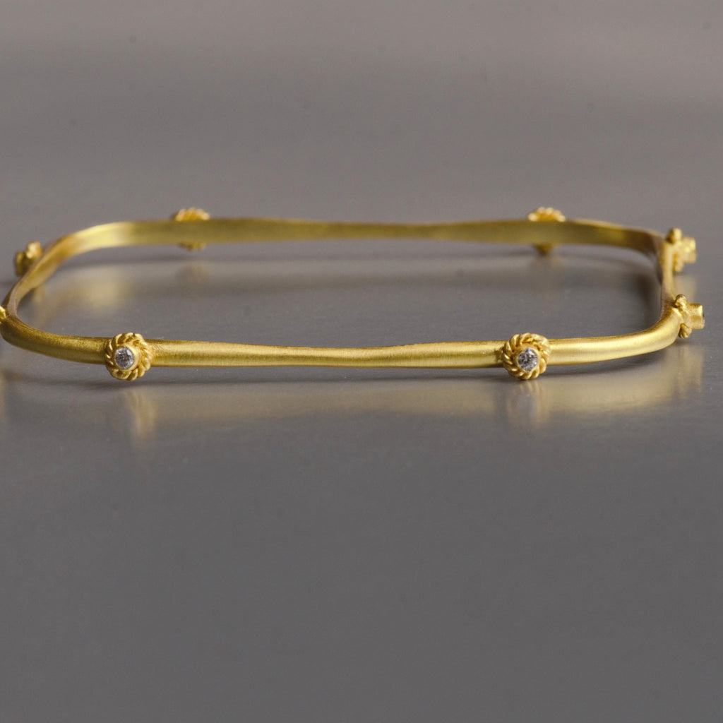 Handmade, asymmetrical, this modern bracelet is augmented with 8 cubic zirconia and artistic bezel set adorn the arm as unique wearable art. It is made with brass and plated efficiently with 18kt gold. The bracelet is 7.5 cm in diame