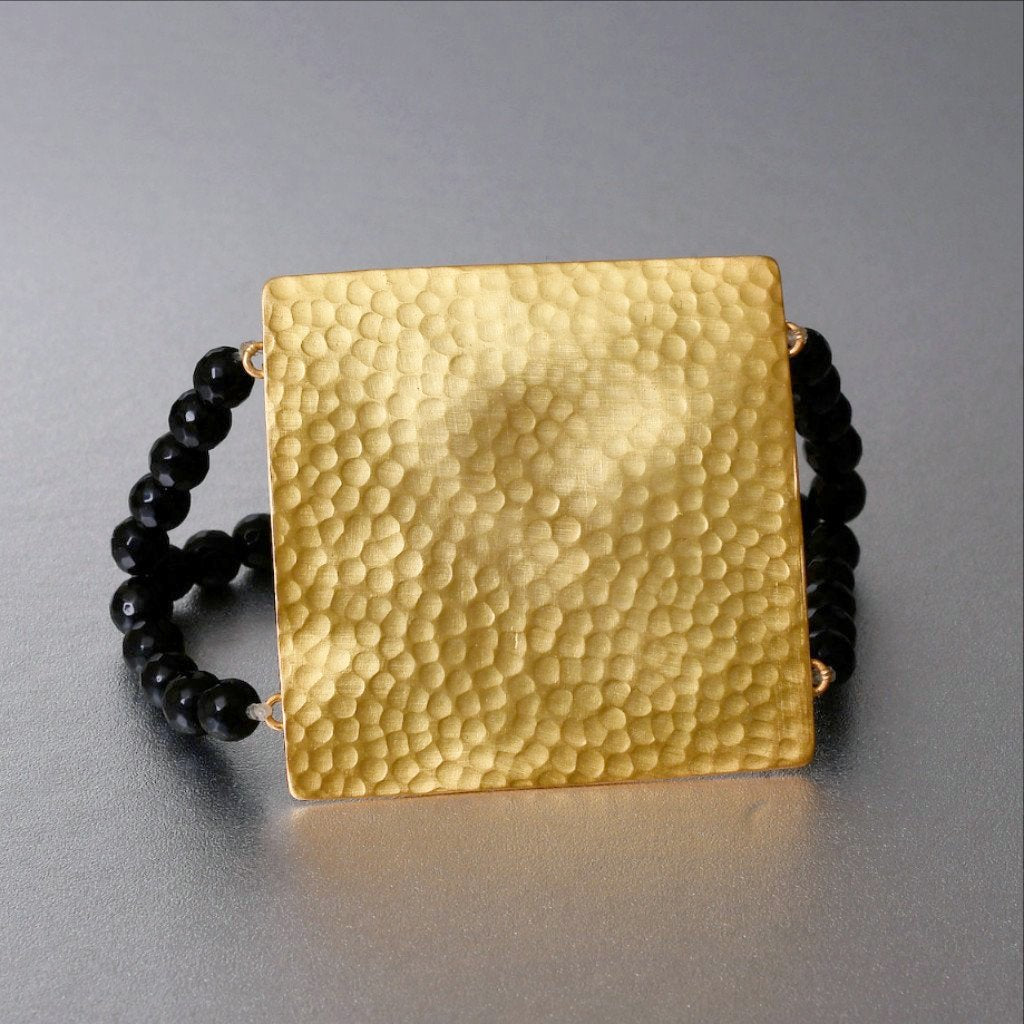 A little outside the box, one may say. A somewhat chunky design that incorporates a luxe boho appeal to an earthy yoga culture. A stretchable bracelet to make the bracelet sit in the manner you want. The bracelet is gold plated on brass with 2 rows of black onyx beads.