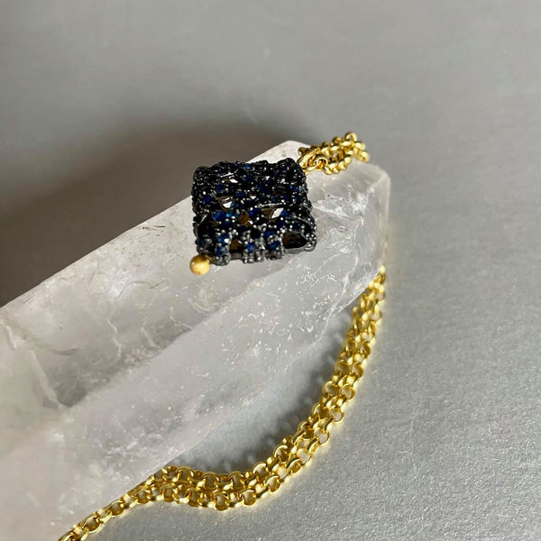  Round-shaped blue sapphires that weigh 1.87 gms and are 1.50 mm in size are studded meticulously on this stunning square-shaped pendant, which is 25x18mm in height and width. and in a .925 sterling silver necklace with 18kt gold plating. This sterling silver chain necklace with fine gold plating is 16 inches long. 