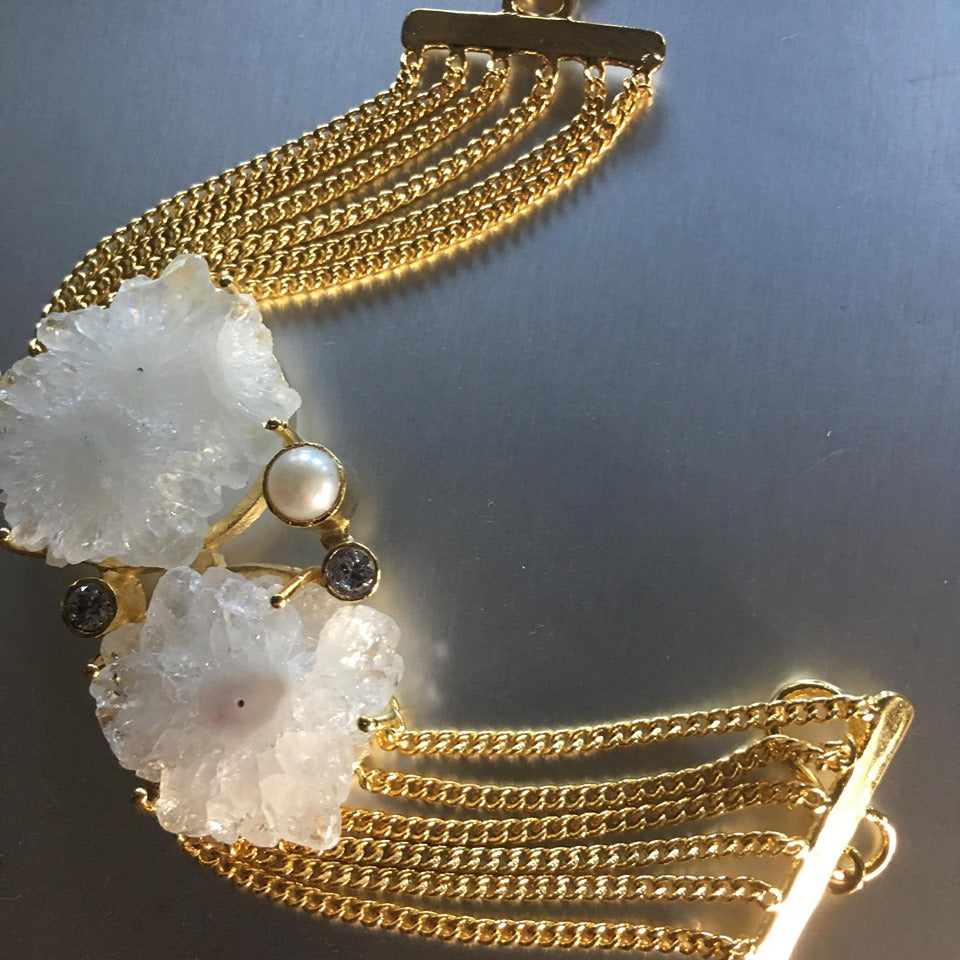 A magnificent creation, a designer's masterpiece. Sundari bracelet showcases huge white druzy crystals along with cubic zirconia to add that perfect bling and pearls to create a unique, gold plated chain bracelet.