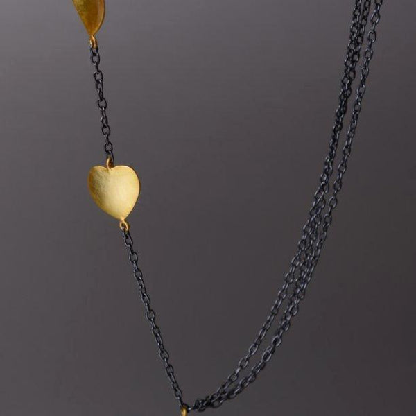 Merak Necklace: A unique amalgamation of chains and adorable heart charms. One side flaunts 3 chains, the other side showcases cute little gold plated heart charms.