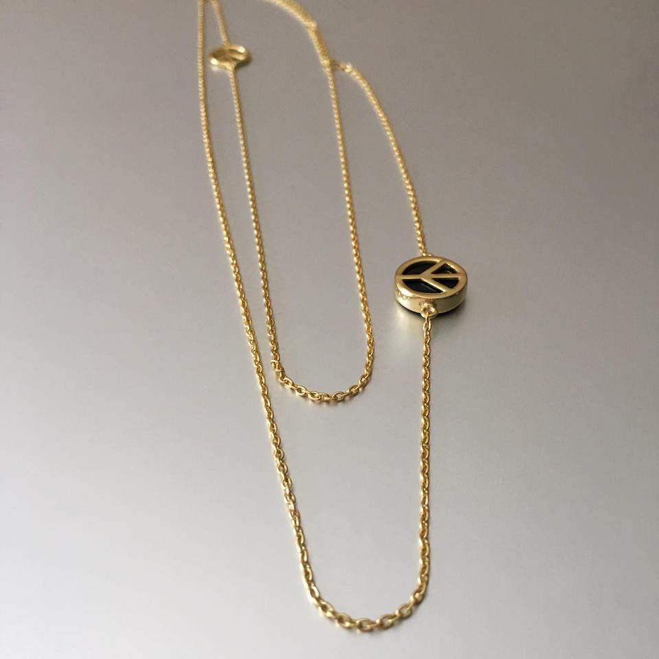 Double, gold plated chain necklace, one longer than the other hold a plain peace sign on one chain and a chunkier one with black onyx on the longer chain. 